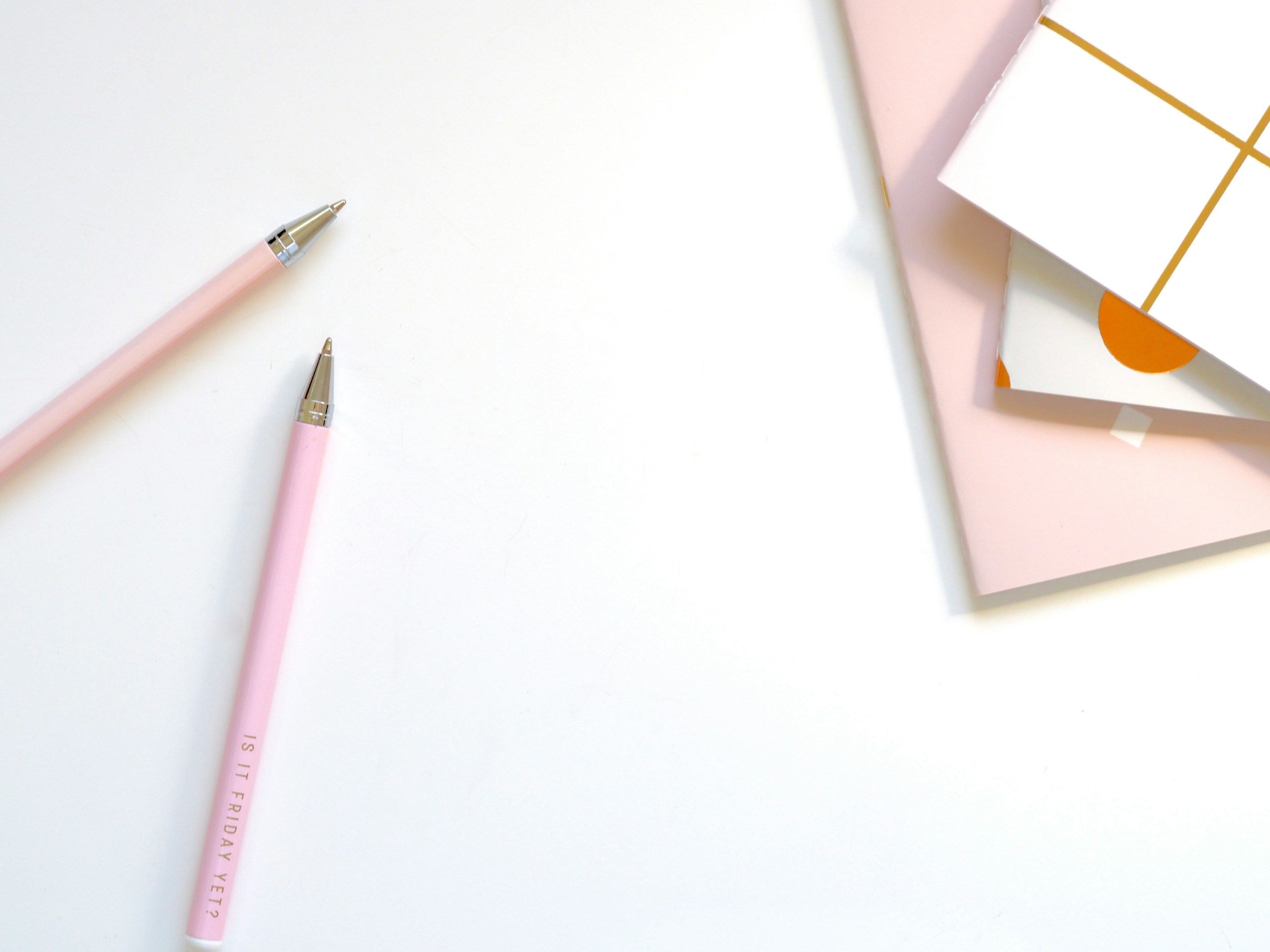 two colorful pens resting beside an open book on a bright desk